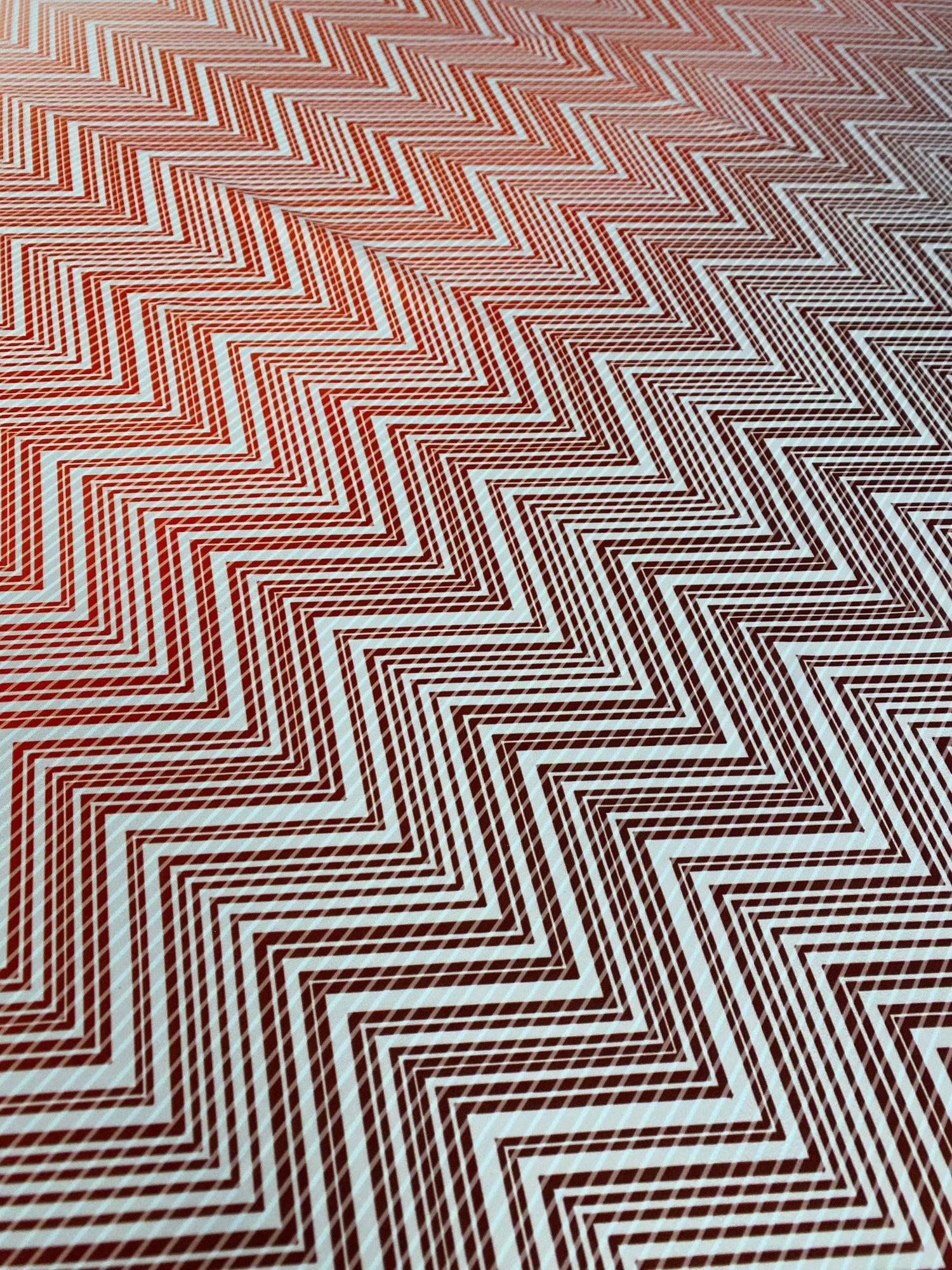 Close-up of red and white chevron patterned fabric with a textured surface and 150cm width, ideal for sewing and crafting projects