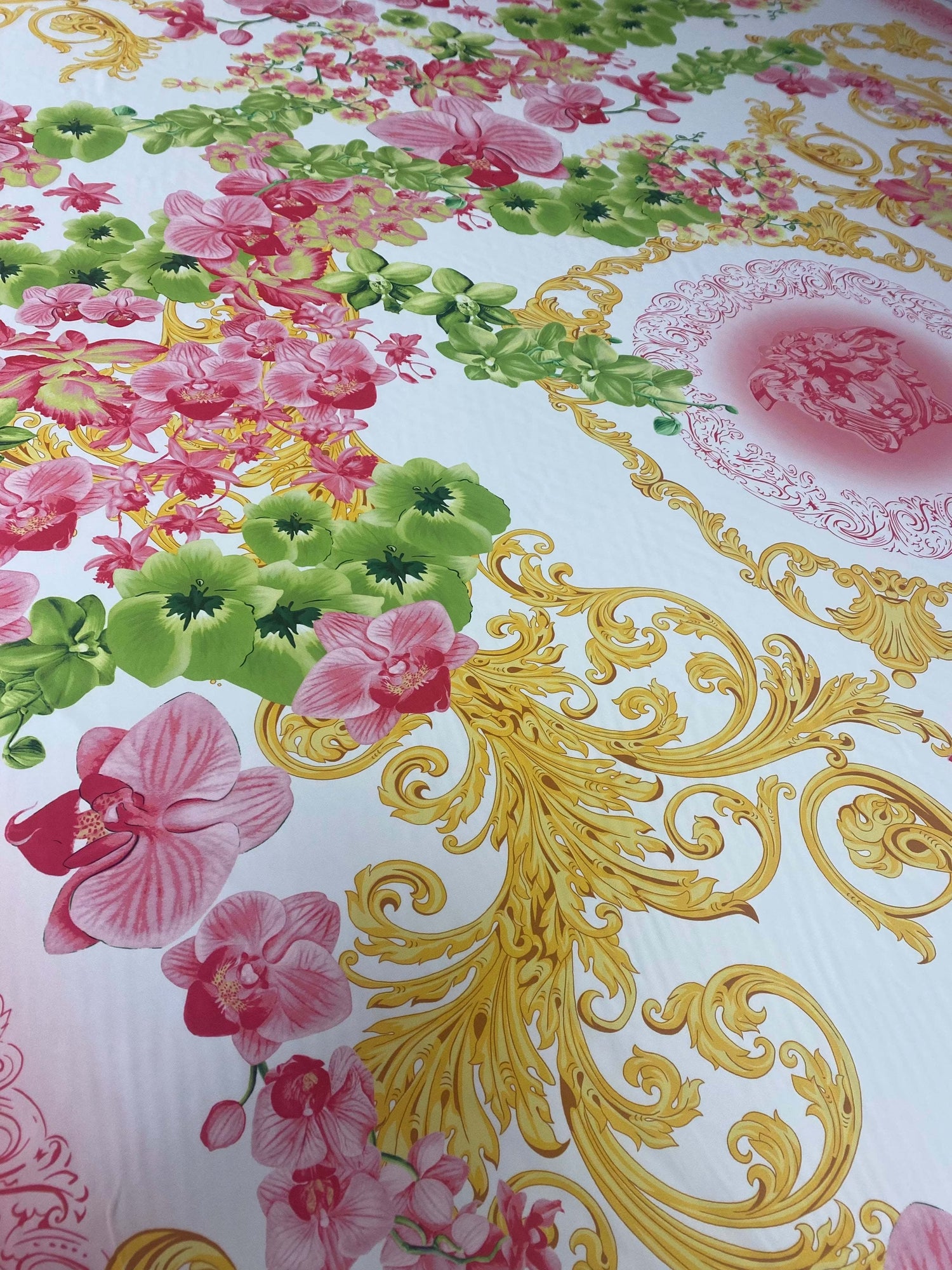 Orchid swirl print fabric with pink floral and green leaves pattern on white background with gold decorative swirls