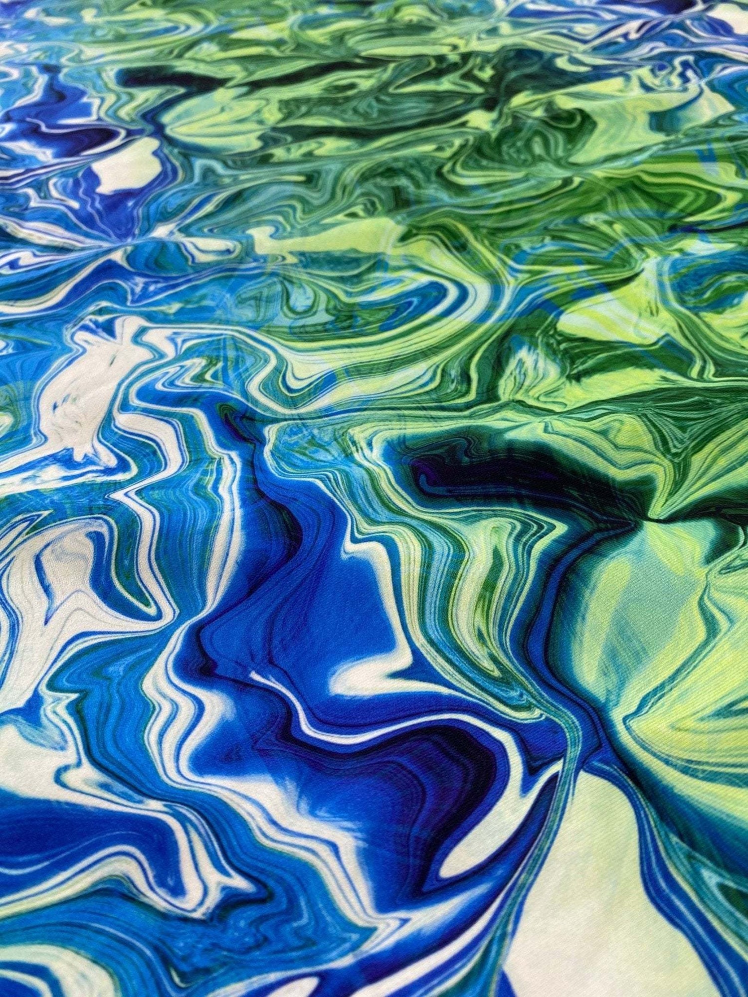 Close-up of blue and green abstract wave patterned fabric with vibrant swirling design