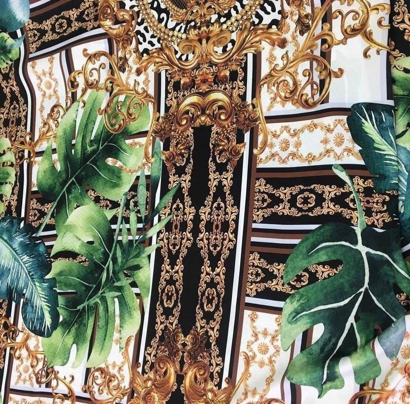 Baroque tropical green and gold fabric with ornate baroque patterns and large green tropical leaves on a black and white background
