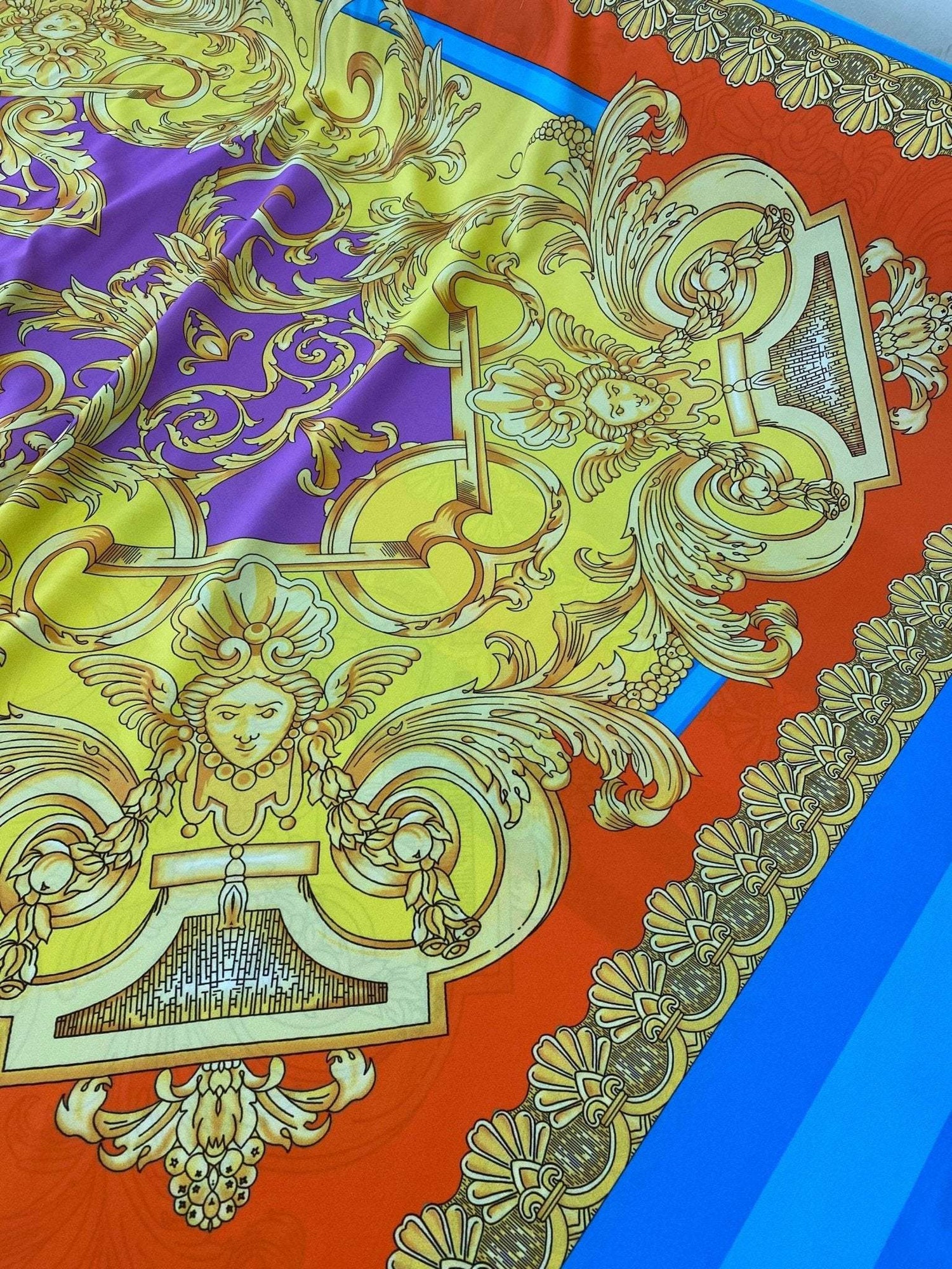 Baroque pattern silky crepe fabric in vibrant orange, blue, and purple with ornate gold detailing and intricate designs