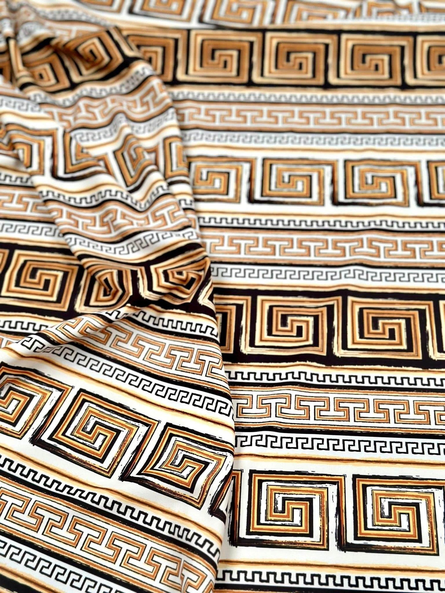 Beige brown silky crepe fabric with geometric Greek key pattern and smooth drape