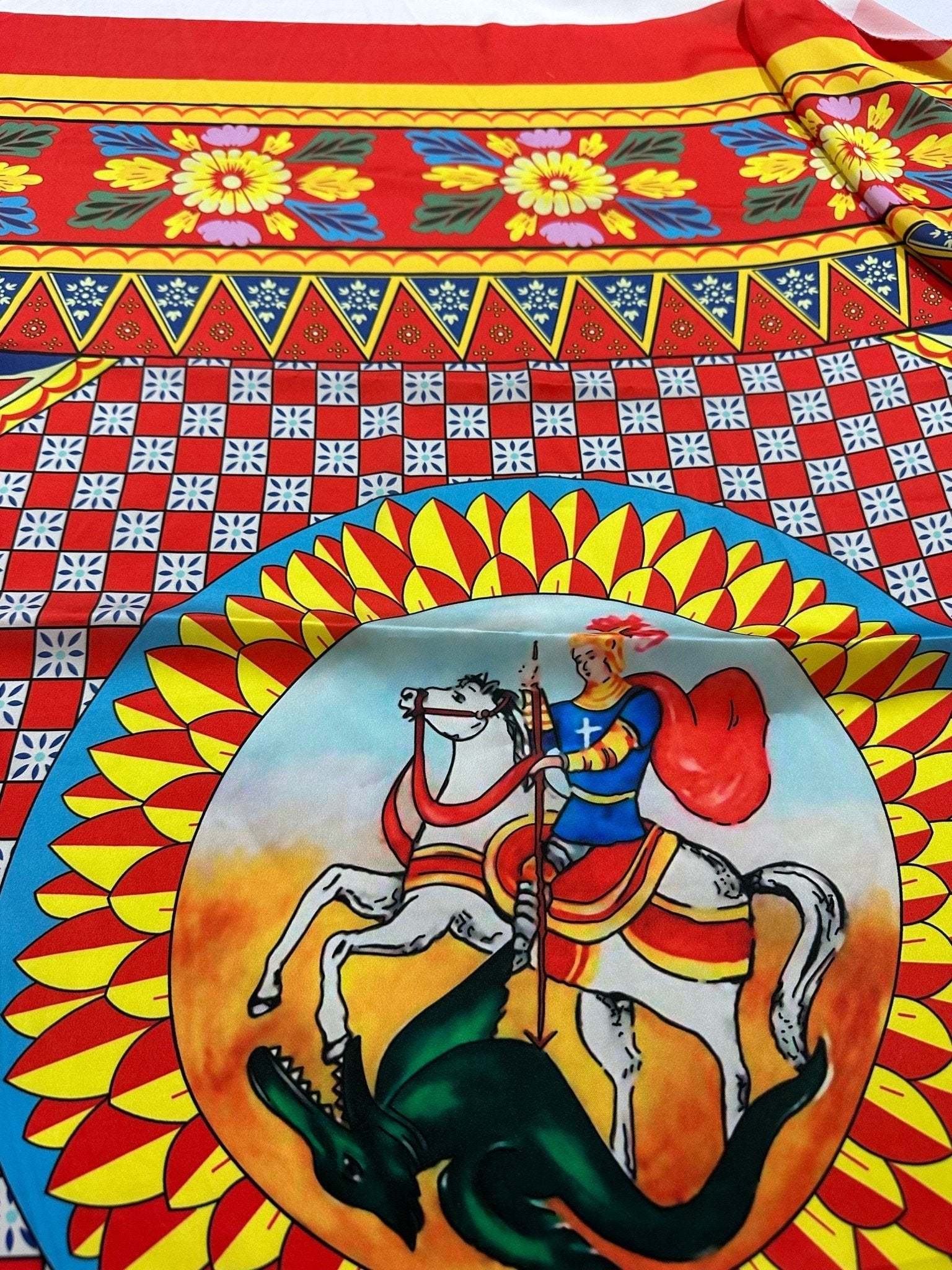 Caretto Scilly designs fabric with vibrant geometric patterns and a detailed knight on horseback illustration in red, yellow, and blue colors
