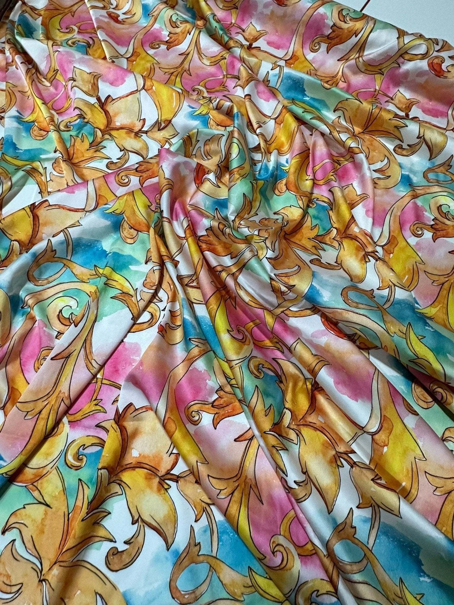 Colorful Baroque Floral Fabric with vibrant gold, pink, blue, and white intricate floral patterns and a glossy finish