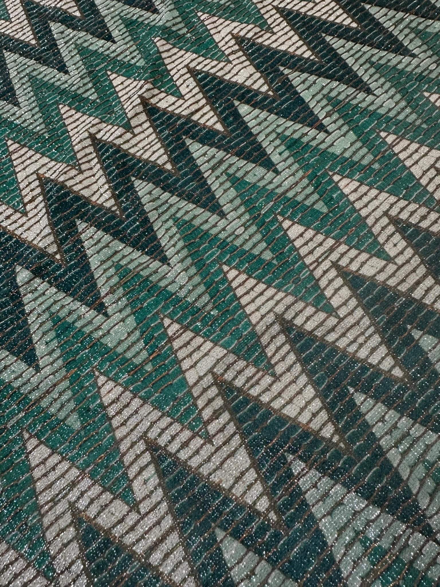 Close-up of green zigzag pattern gold lurex fabric with glitter knit texture and 4-way stretch.
