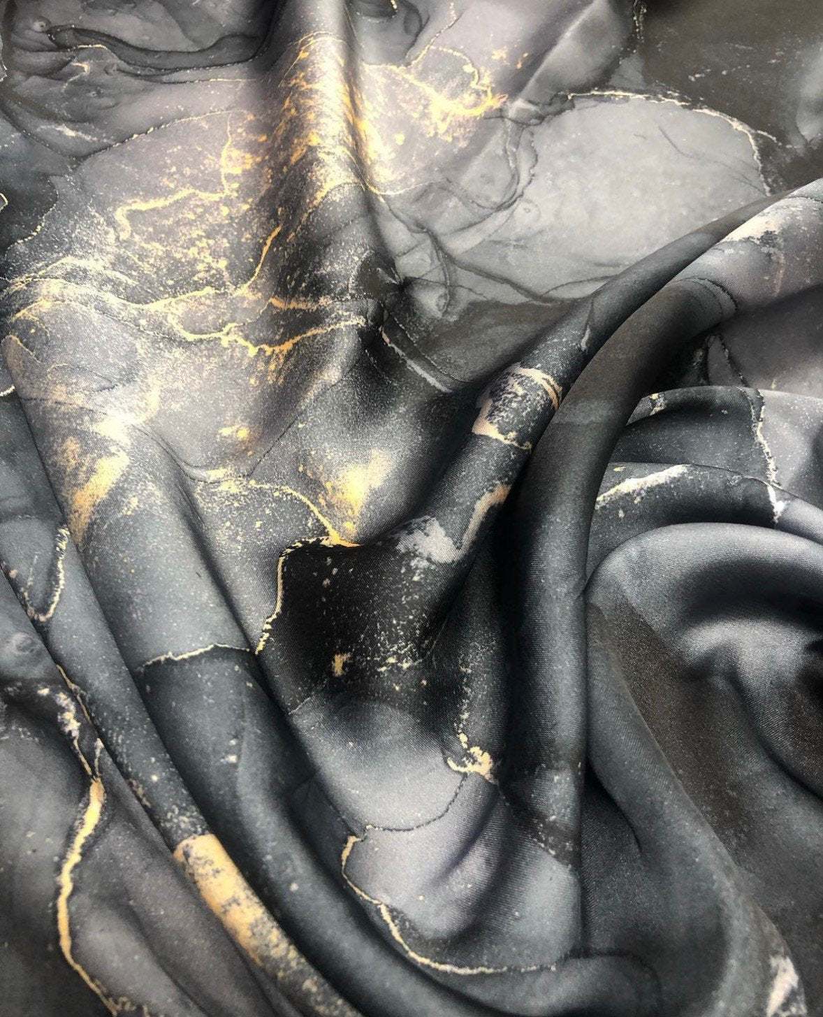 Gray tie dye fabric with gold accents in a smooth, flowing texture for fashion and decor projects