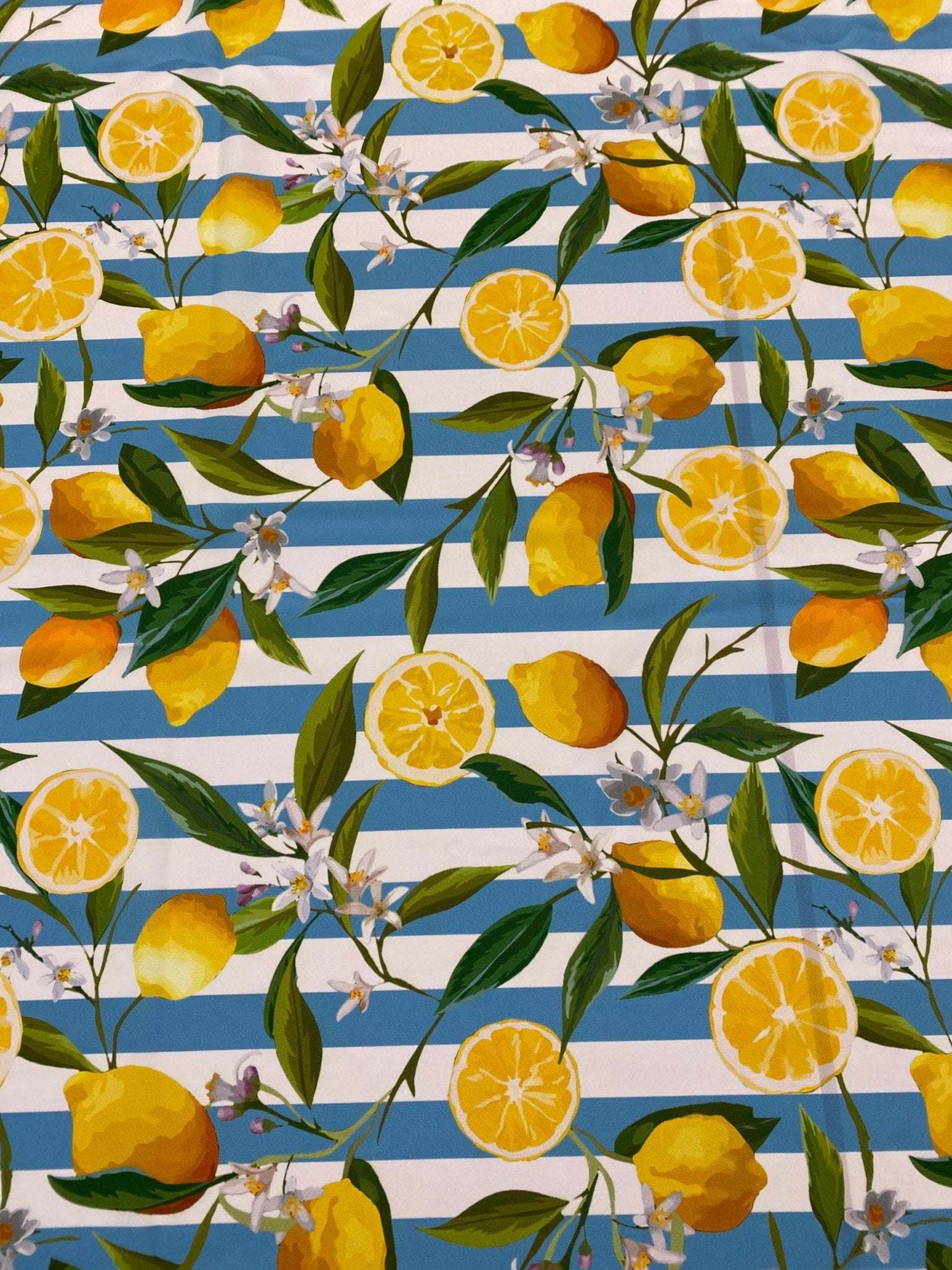 Lemon and floral print fabric on blue and white stripes with green leaves and white blossoms