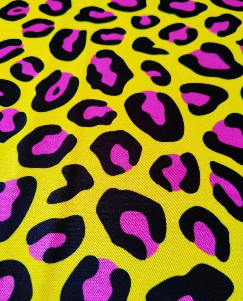 Yellow leopard print fabric with pink and black spots, bold animal pattern textile for fashion and decor projects
