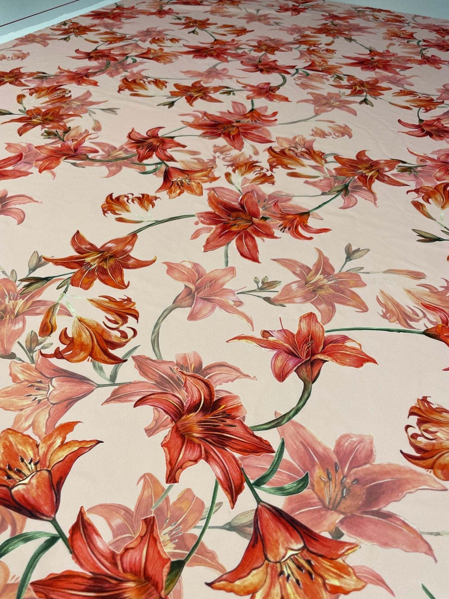 Orange and red lily floral fabric with vibrant flower pattern on soft material for sewing and crafting projects