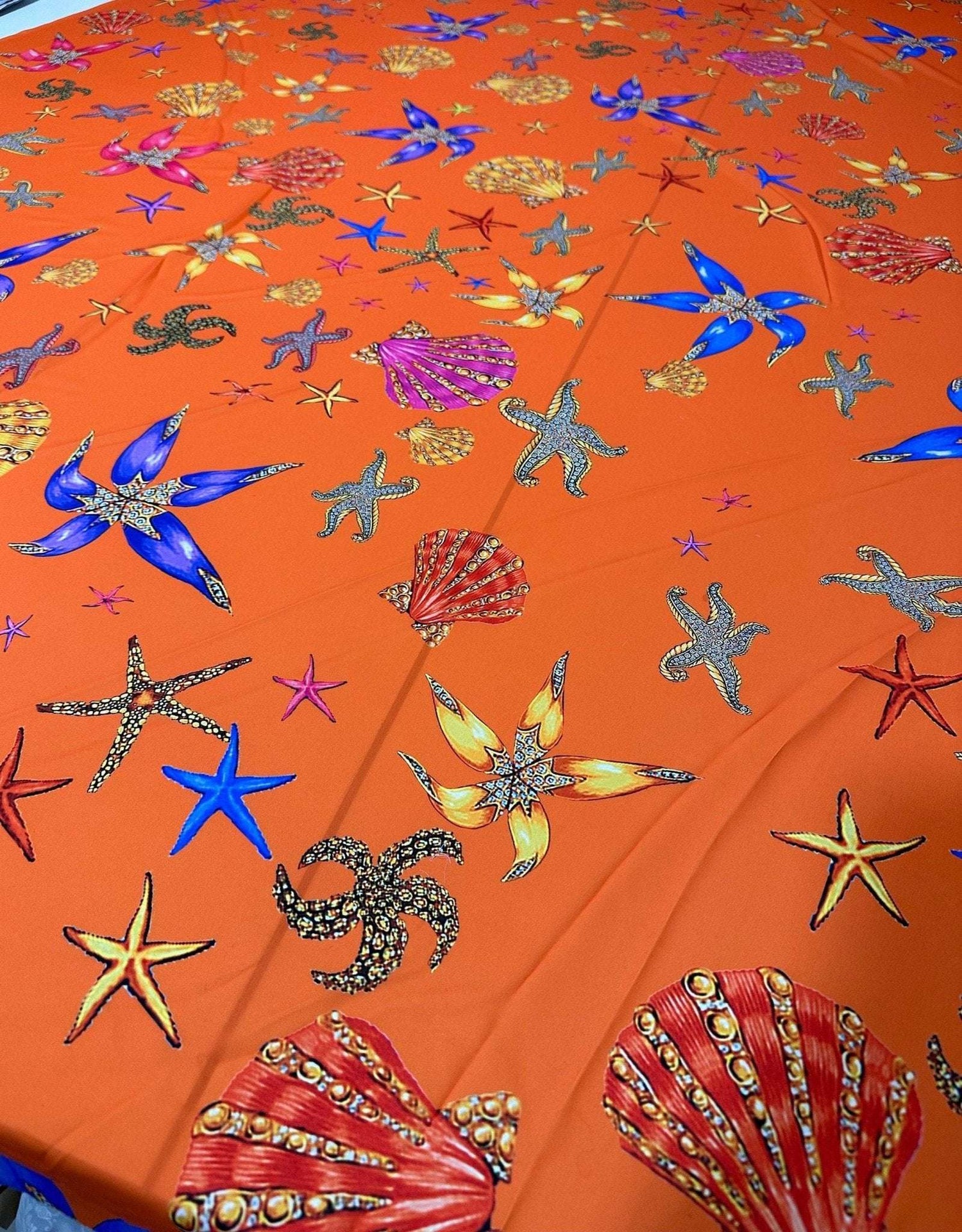 Orange fabric with colorful oyster and sea shell pattern for sewing and crafting projects