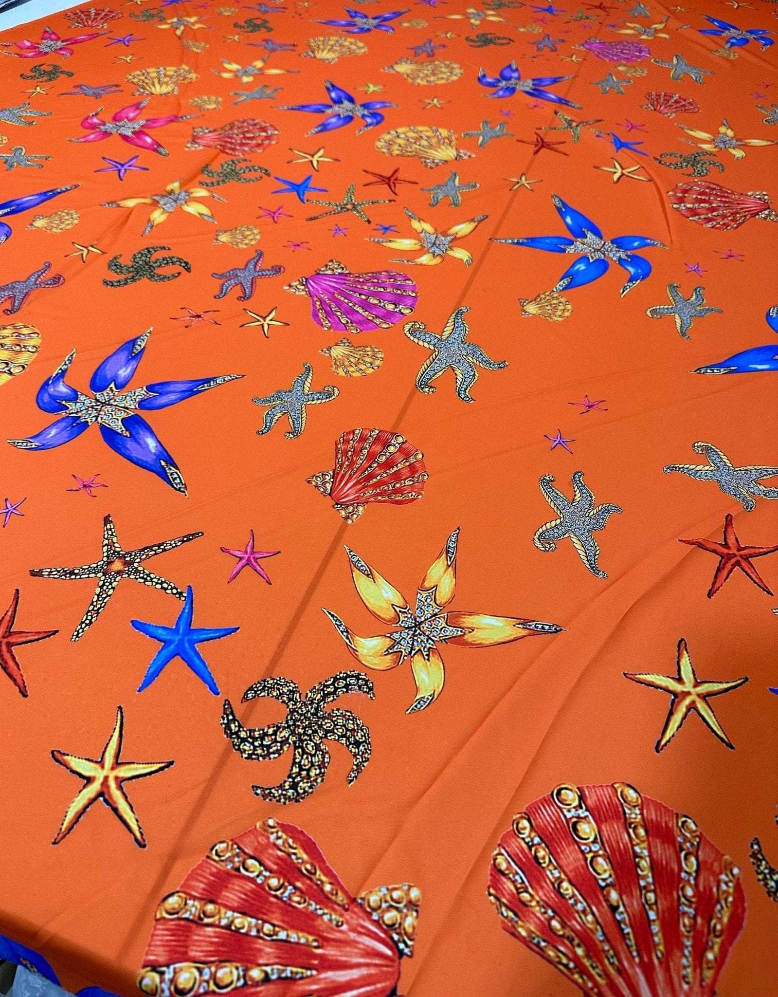 Orange fabric with colorful oyster and sea shell pattern for sewing and crafting projects