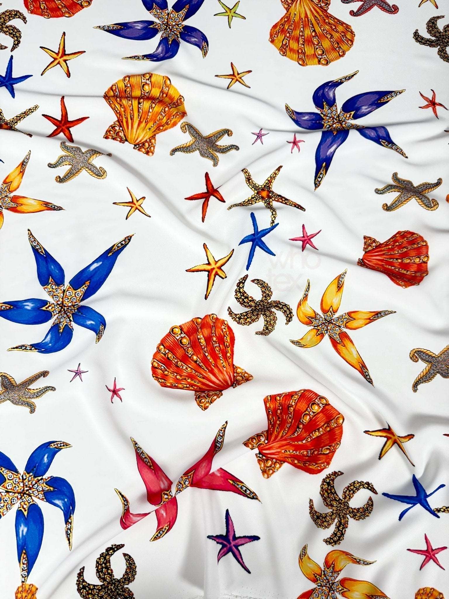White sea shell fabric with colorful starfish and shell patterns perfect for coastal-themed sewing projects