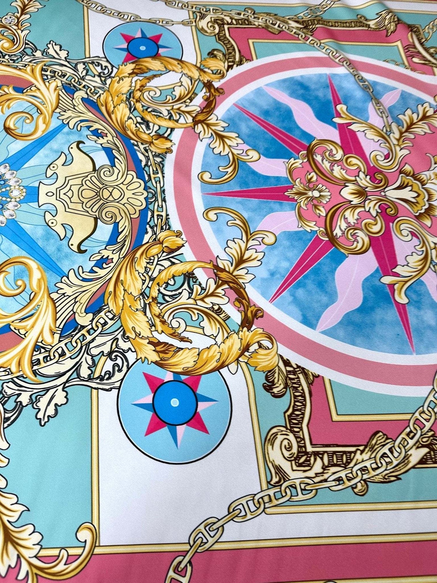 Baroque chain pattern fabric with ornate gold scrolls, compass motifs, and pastel blue and pink background