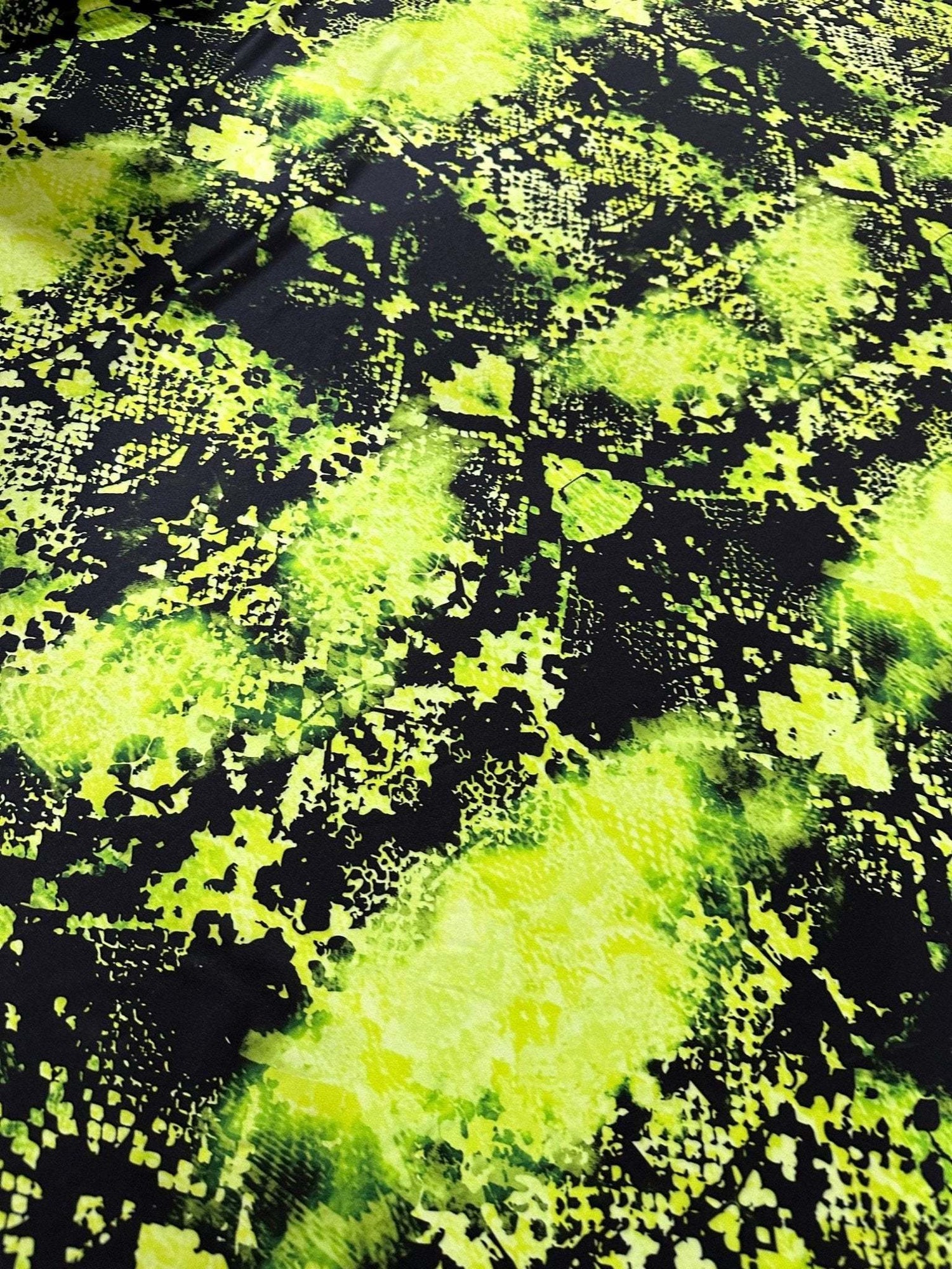 Neon green spandex fabric with black snake skin pattern, stretchy and vibrant material for activewear and costumes