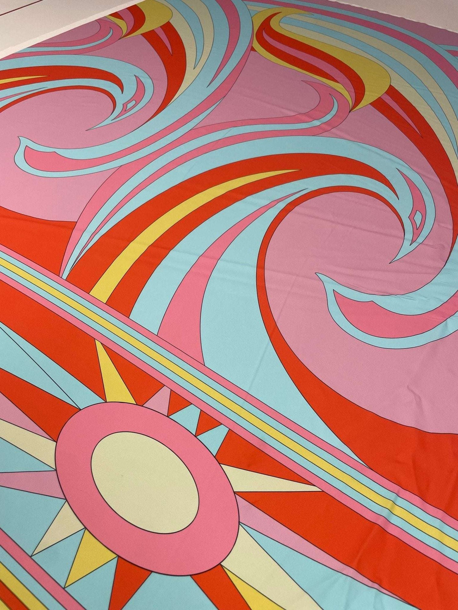 Retro psychedelic swirl and sun print fabric in pink, red, blue, and yellow colors with vibrant retro patterns.