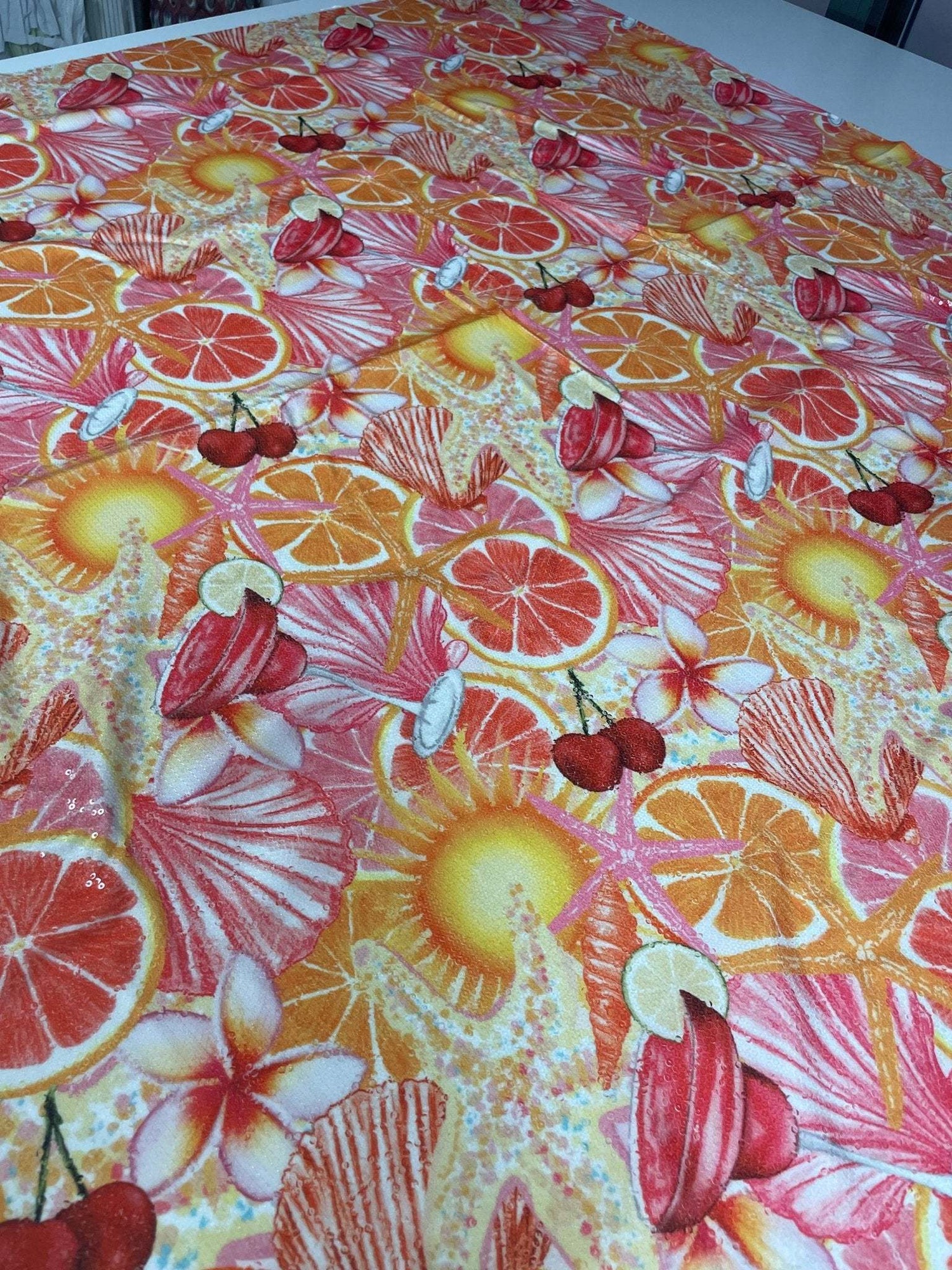 Tropical Citrus Sequin Fabric with vibrant orange, yellow, red citrus slices and starfish design on stretchy floral fabric