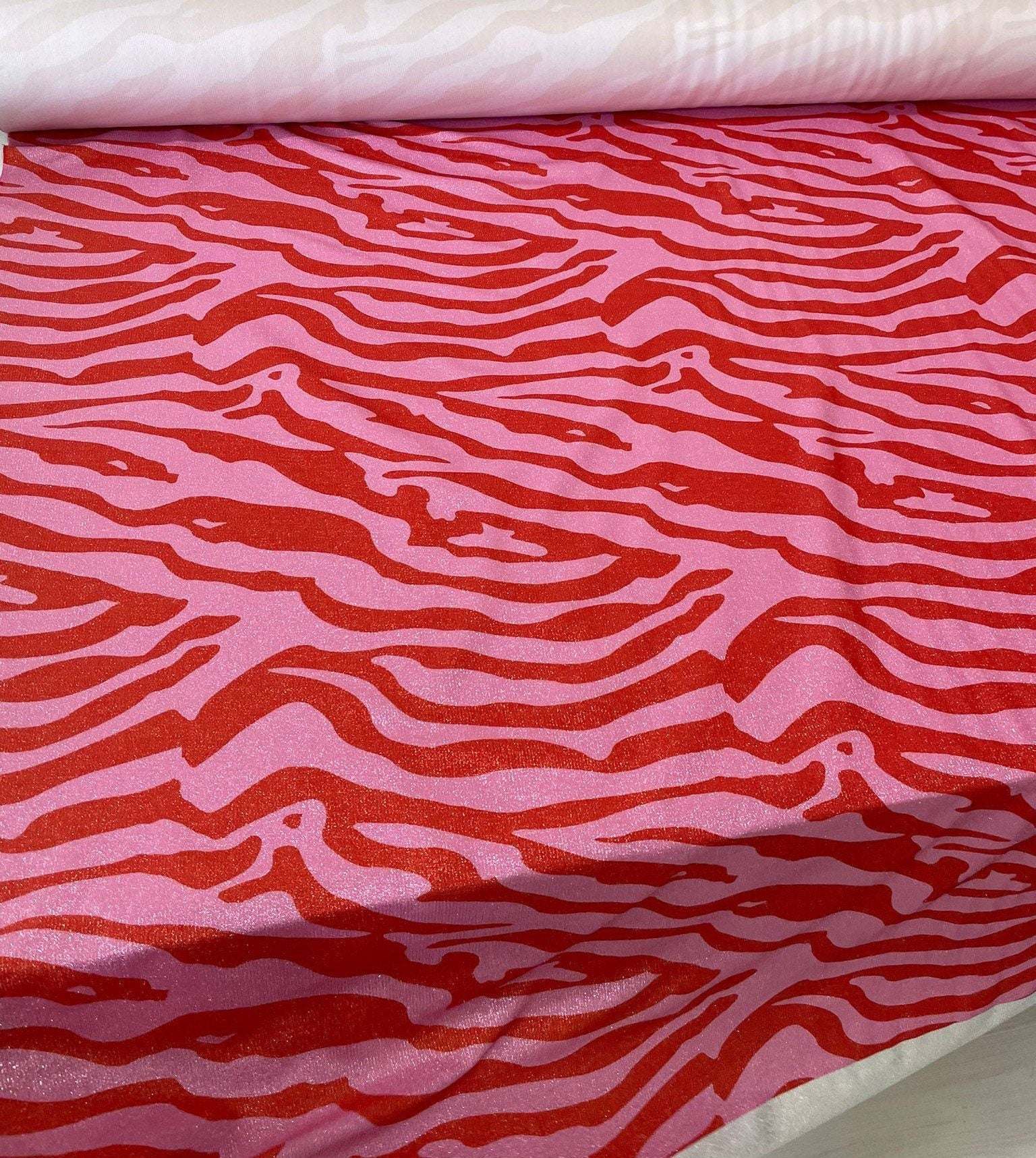 Close-up of zebra pattern 4-way stretch spandex lurex fabric in red and pink with a smooth satin finish for fashion and crafts