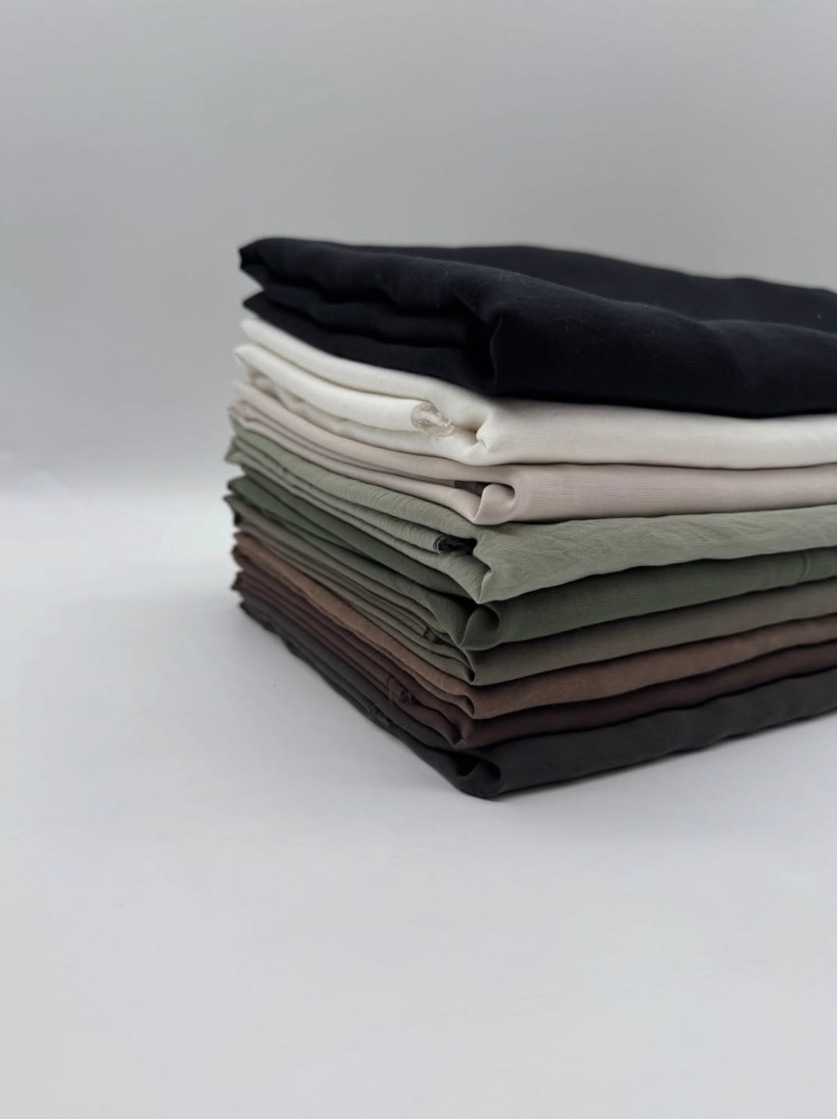 Modal Cupro Fabric by the Metre – Silk-Touch Floss Finish with Elegant Drape, showcasing a stack of various fabric colors.