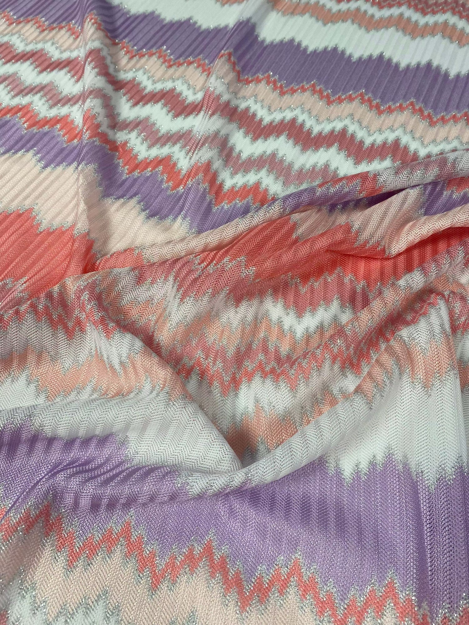 Purple and coral zigzag woven fabric with metallic accents and textured knit mesh pattern