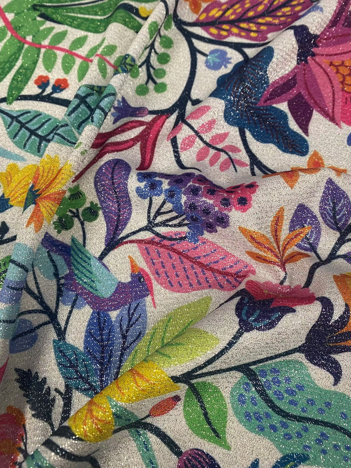 Colorful metallic floral bird pattern Lurex fabric with vibrant flowers, leaves, and birds on a glittery background