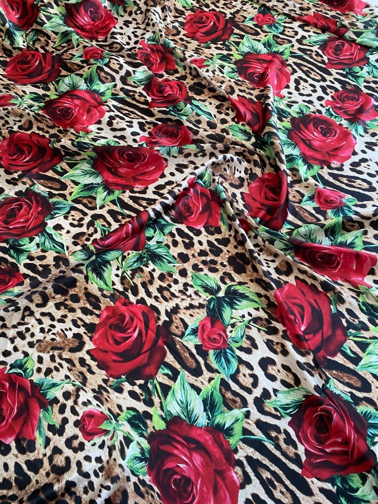 Leopard print fabric with vibrant red rose pattern and green leaves, 150cm wide